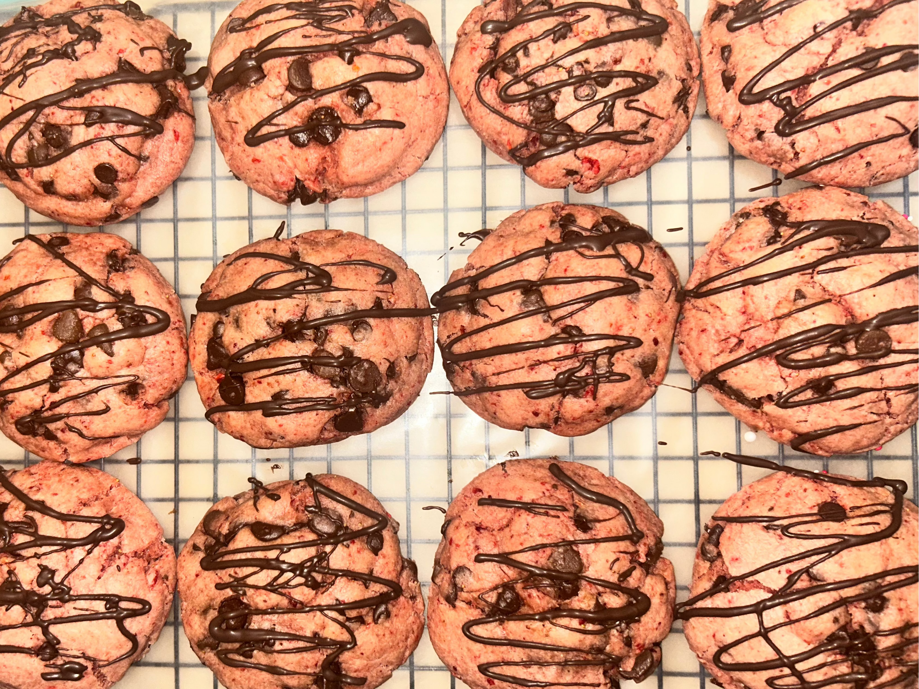 Strawberry cookies with chocolate drizzle on a cooling rack